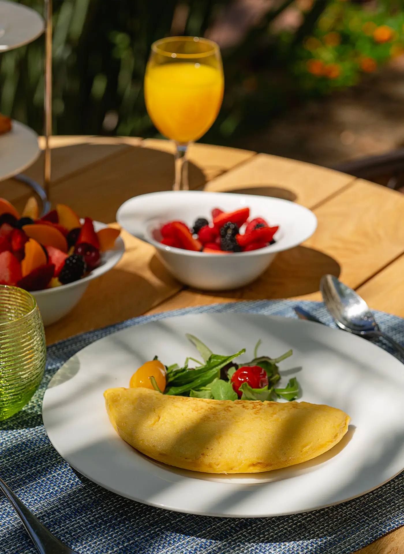 Dettaglio della colazione al Ristorante Federico II con omelette dorata, insalata fresca, ciotole di frutta fresca e spremuta d'arancia.