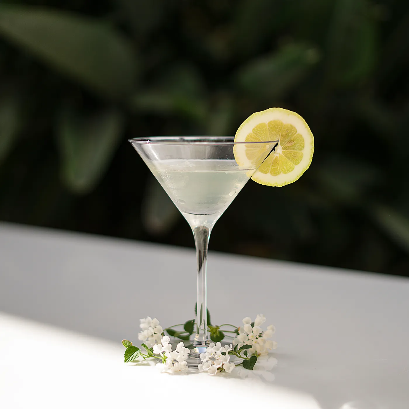 Cocktail in coppa Martini guarnito con una fetta di limone e fiori bianchi alla base, servito al Ristorante Federico II.